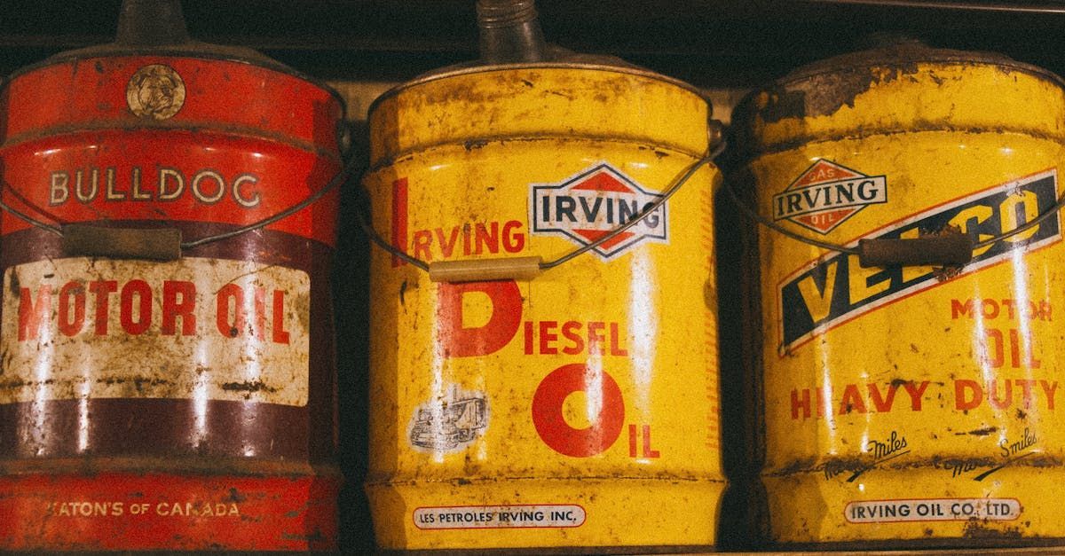 Three vintage oil cans neatly lined up next to each other, with the first can being red and the other two yellow.