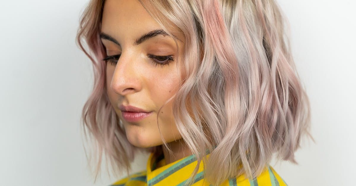 A woman with pink hair is wearing a yellow and green striped shirt.