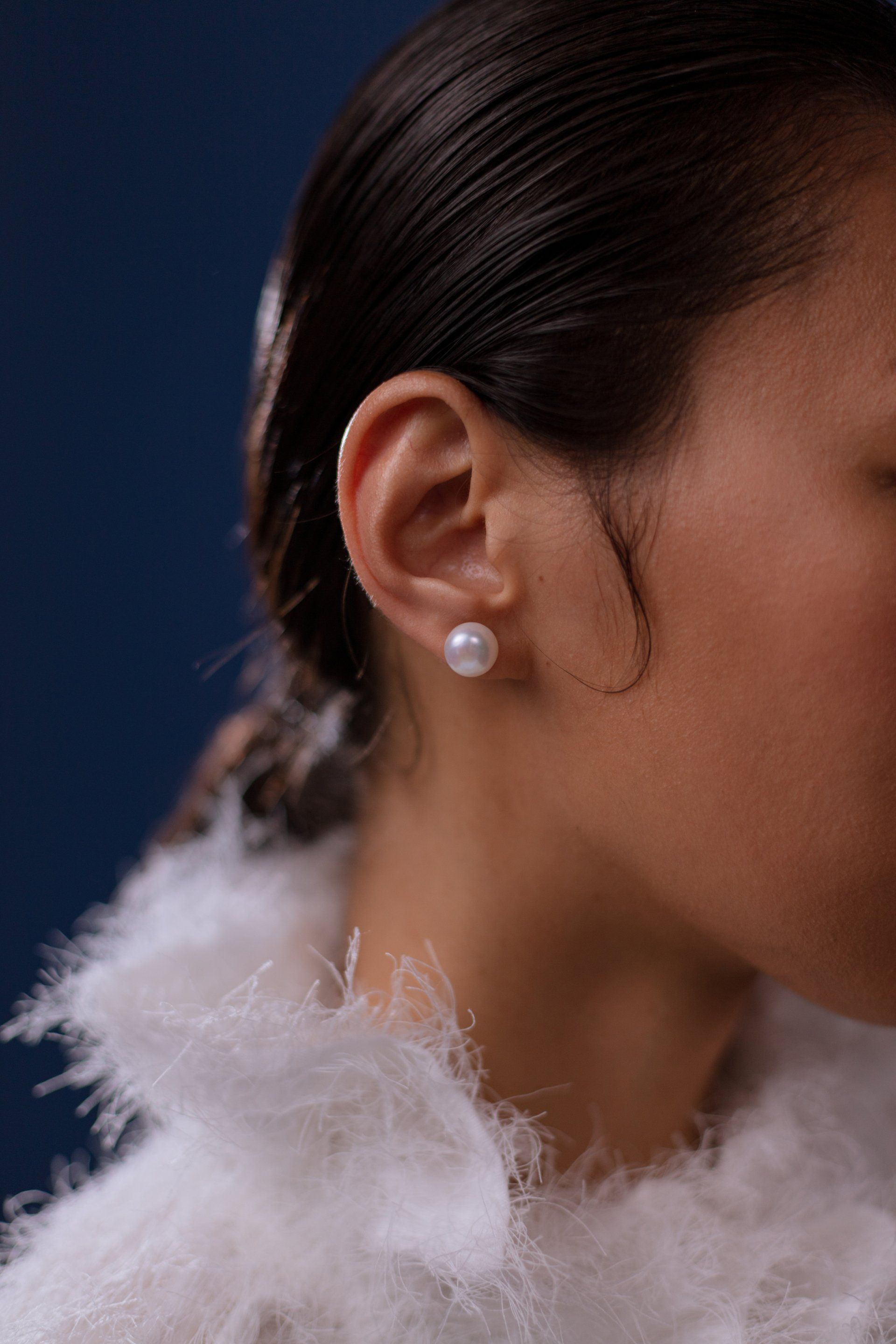 A close up of a woman wearing pearl earrings.