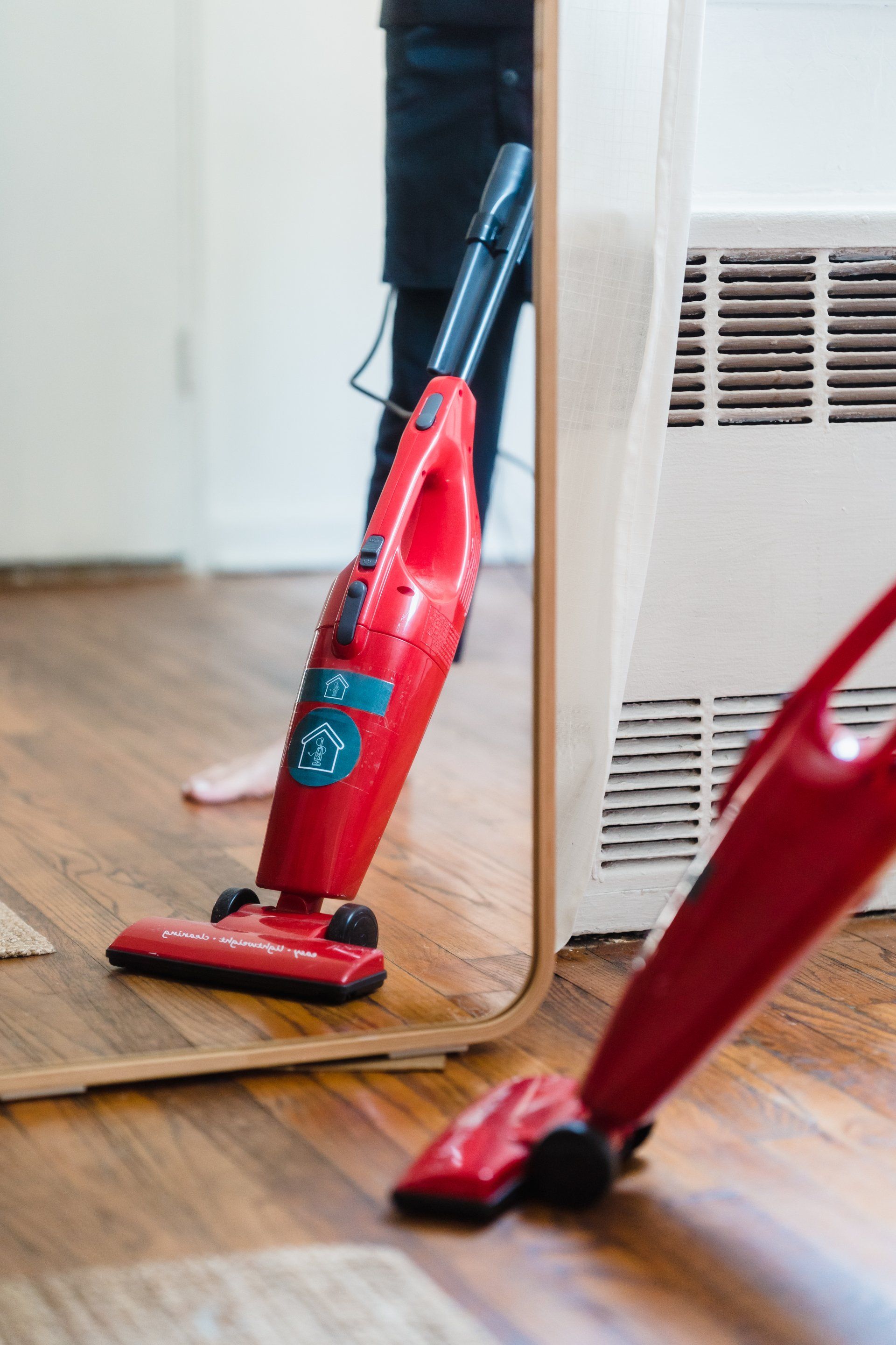 A person is using a vacuum cleaner in front of a mirror