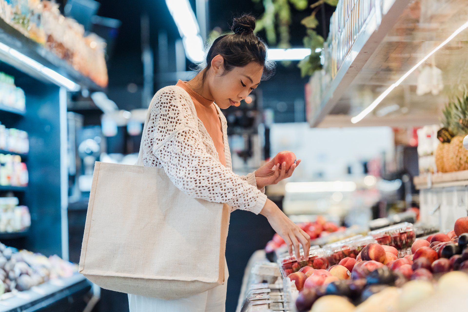 A woman is looking at fruit in a grocery store.