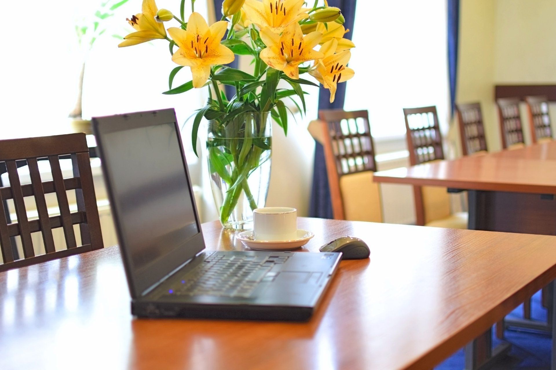 A laptop is sitting on a table next to a vase of flowers.