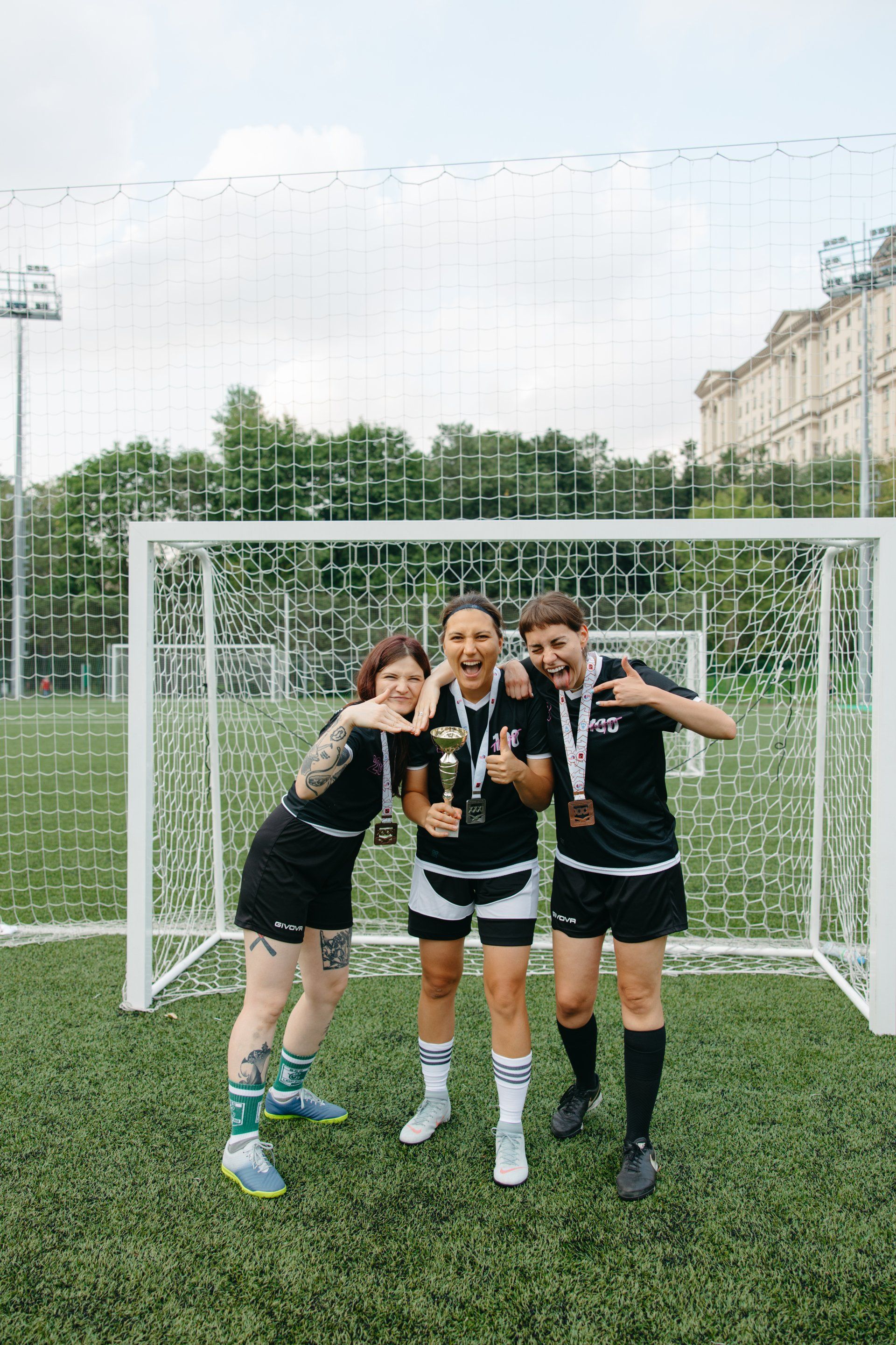 3 happy female soccer players huddle in front of goal