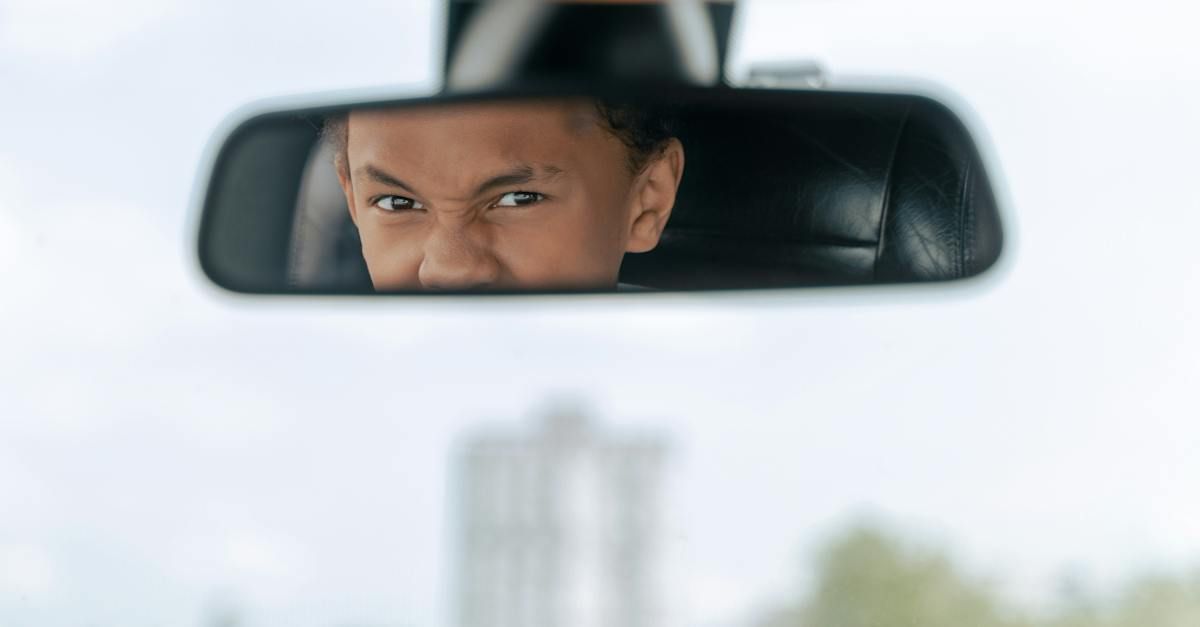 a man is looking at himself in the rear view mirror of a car