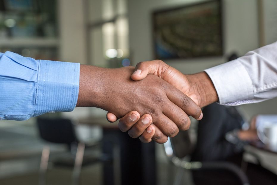 two men are shaking hands in an office .