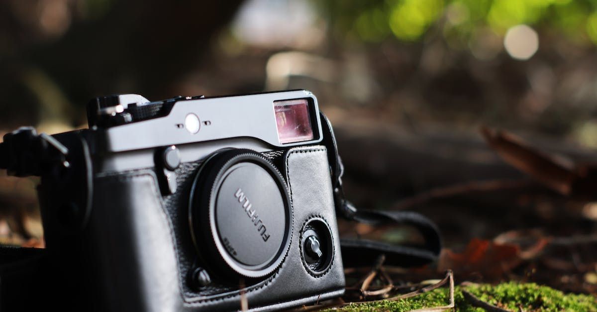 A black Fujifilm rangefinder camera is sitting on a mossy surface.