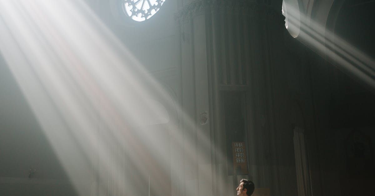 A man is standing in a dark room with the sun shining through a window.