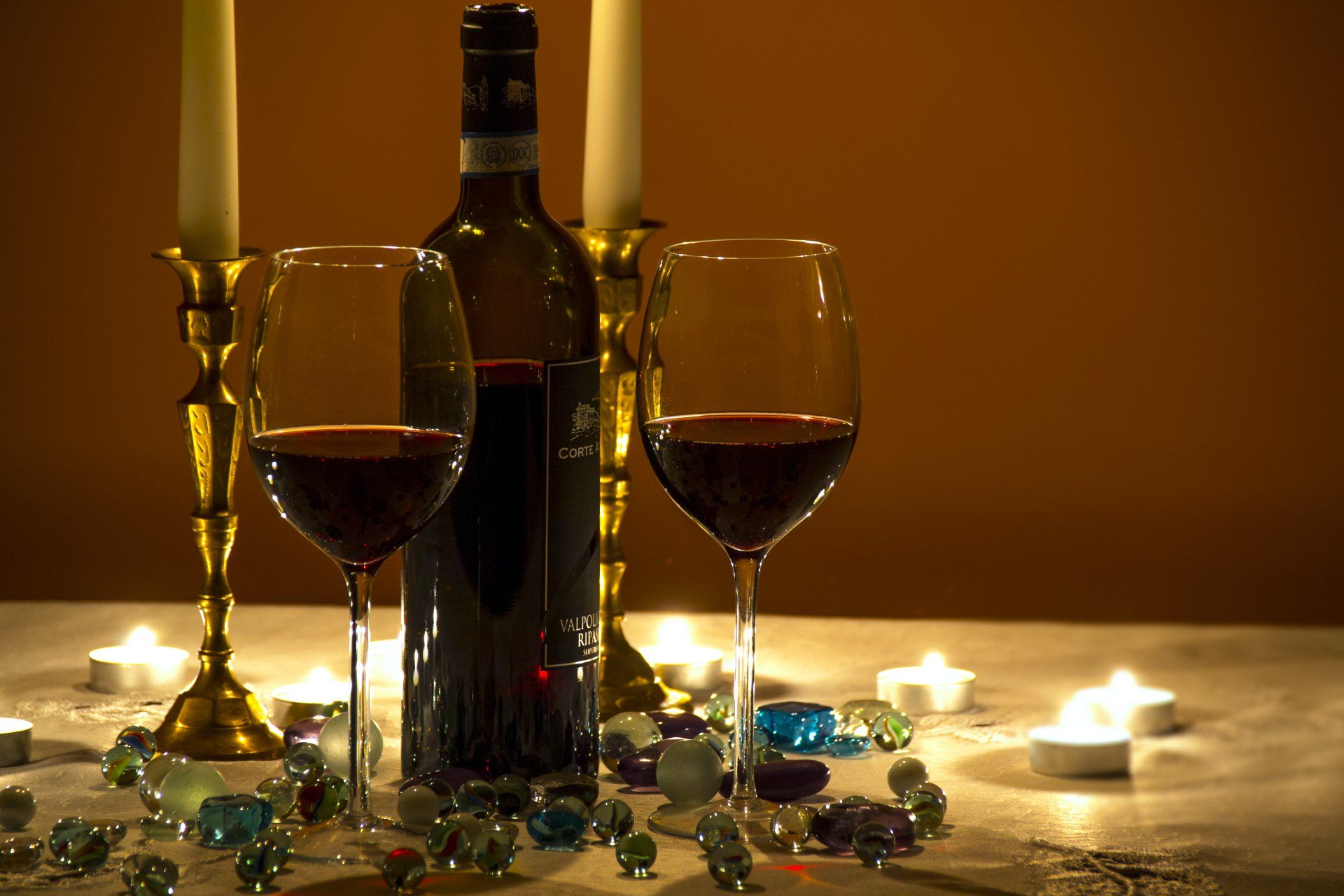 Two glasses of wine and a bottle of wine on a table with candles