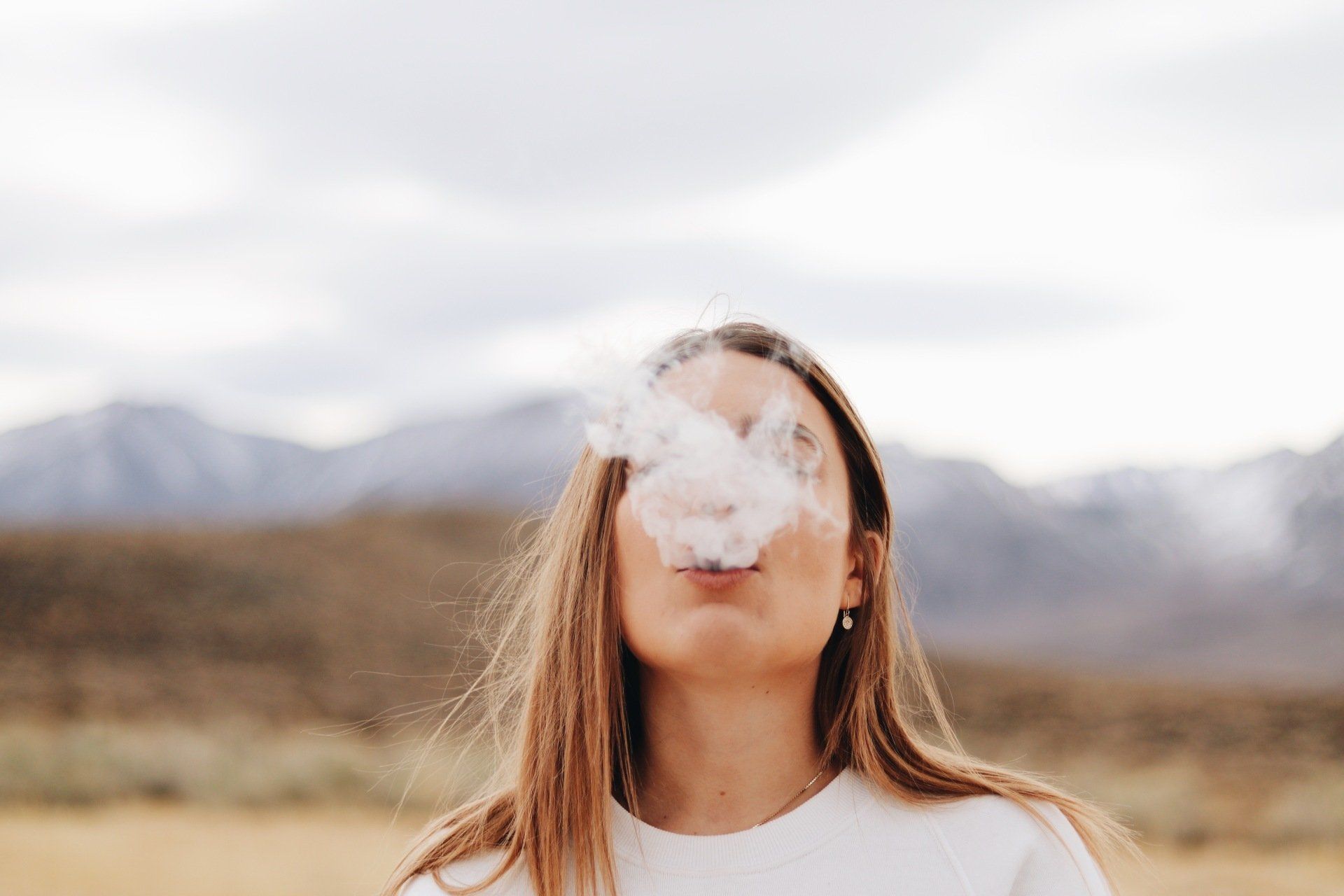 A woman is blowing smoke out of her mouth.