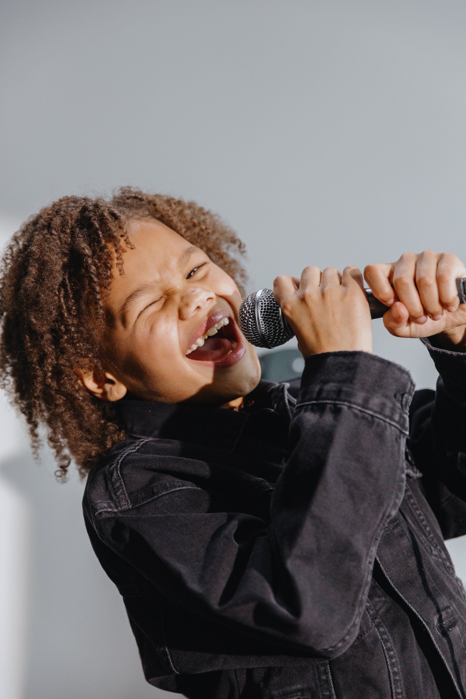 A young boy is singing into a microphone.
