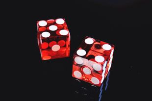 Deux dés rouges avec des points blancs sur une surface noire.