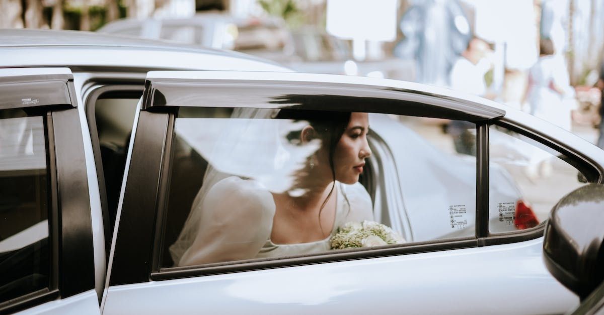 A bride is sitting in the back seat of a car.