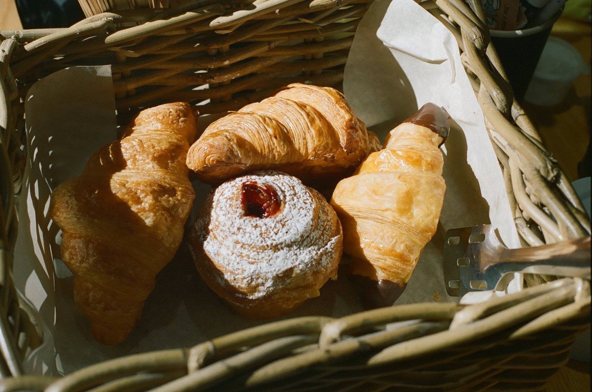 A basket filled with croissants and a donut on a table.