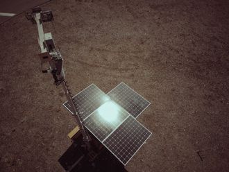 An aerial view of a solar panel sitting on top of a dirt field.