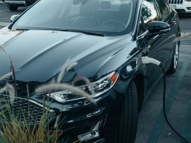 A black electric car is being charged in a parking lot.