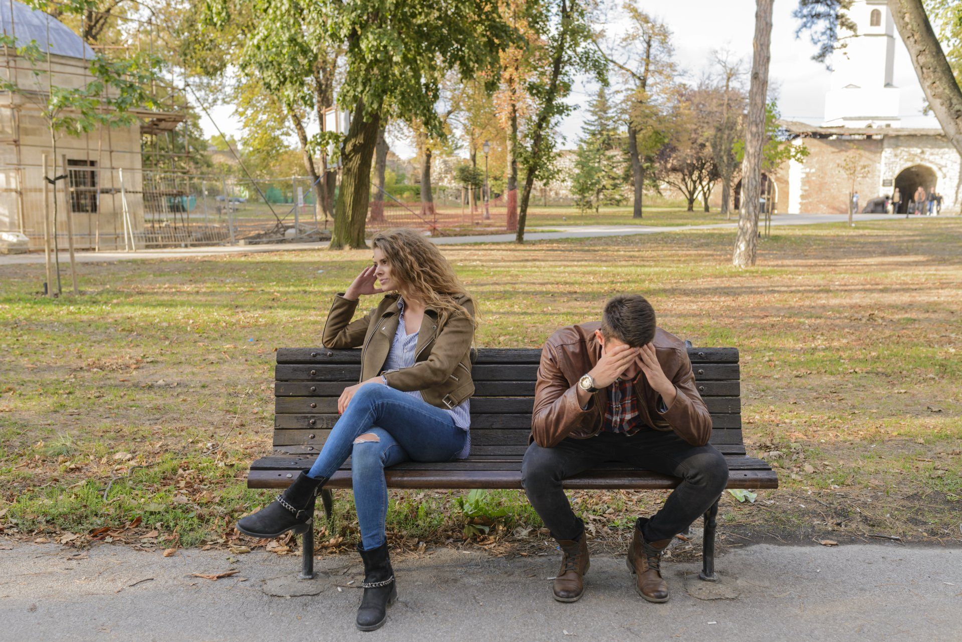 un uomo e una donna sono seduti uno accanto all'altro su una panchina del parco