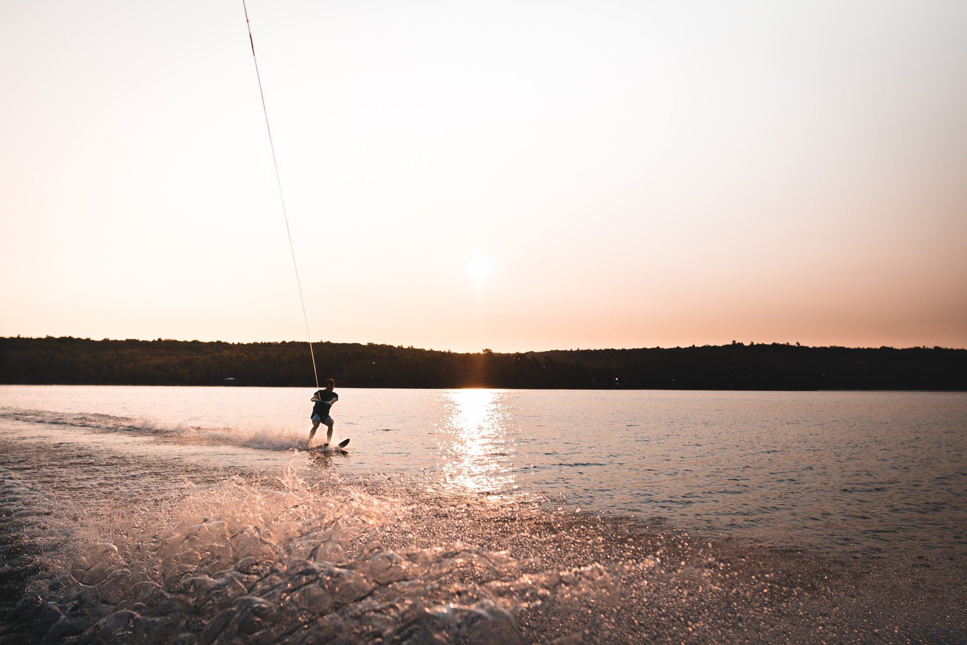 a person is wakeboarding on a lake at sunset