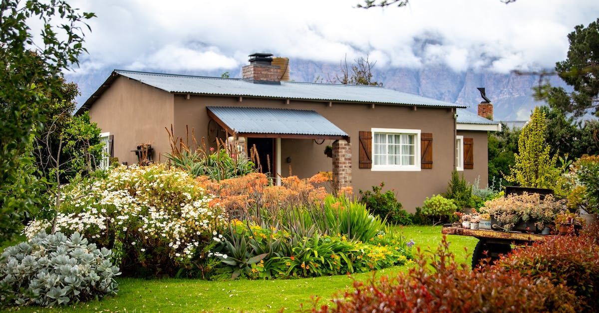 A house with a garden in front of it and mountains in the background.