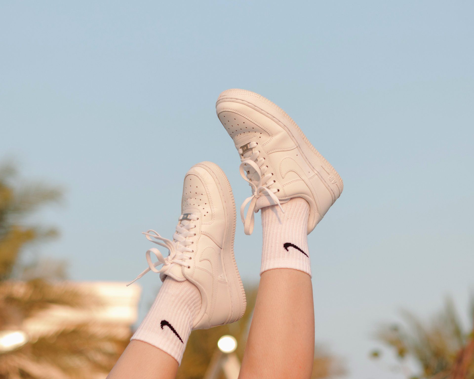 A person is wearing white nike shoes and white socks.