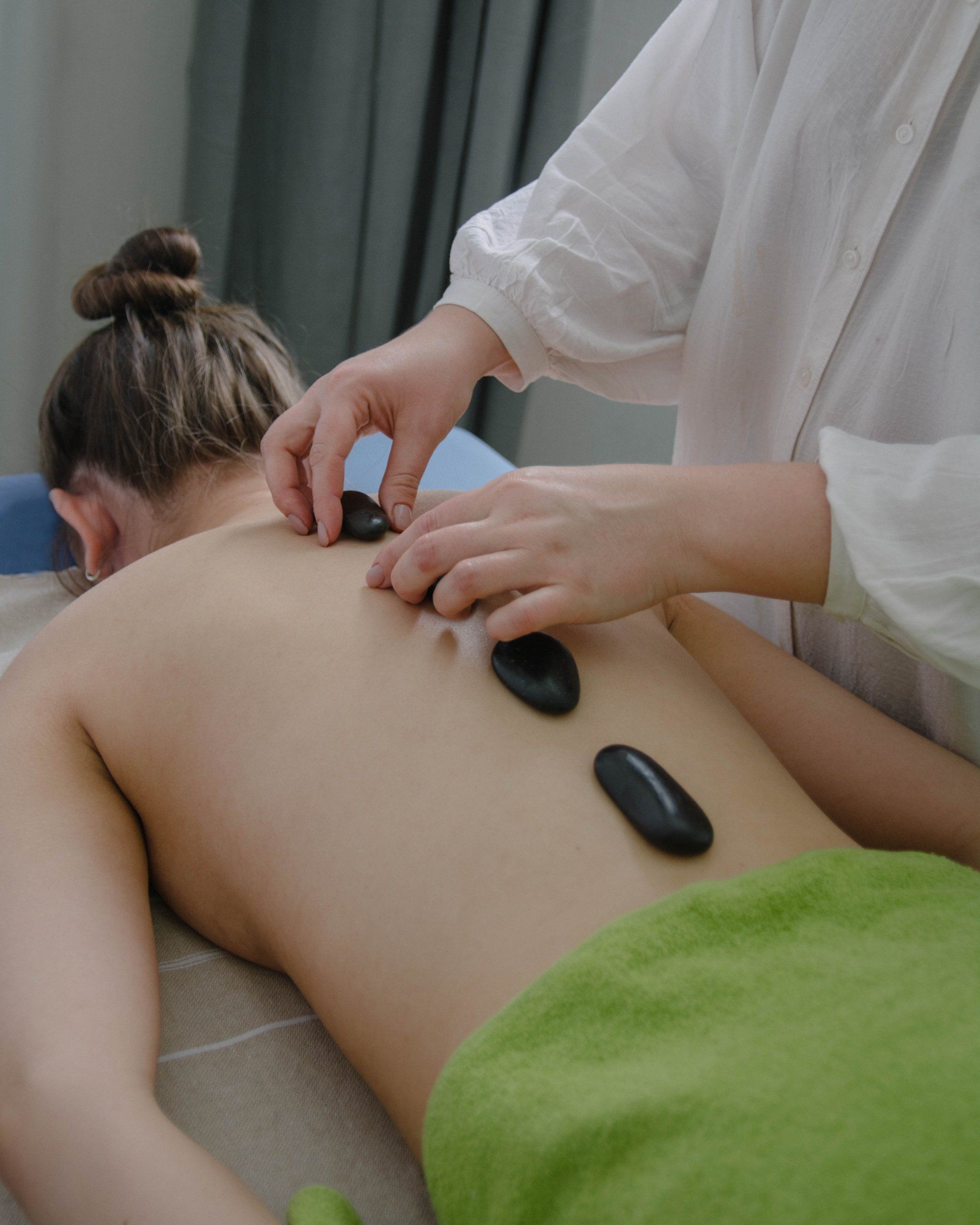 a woman is getting a hot stone therapy with rocks on her back