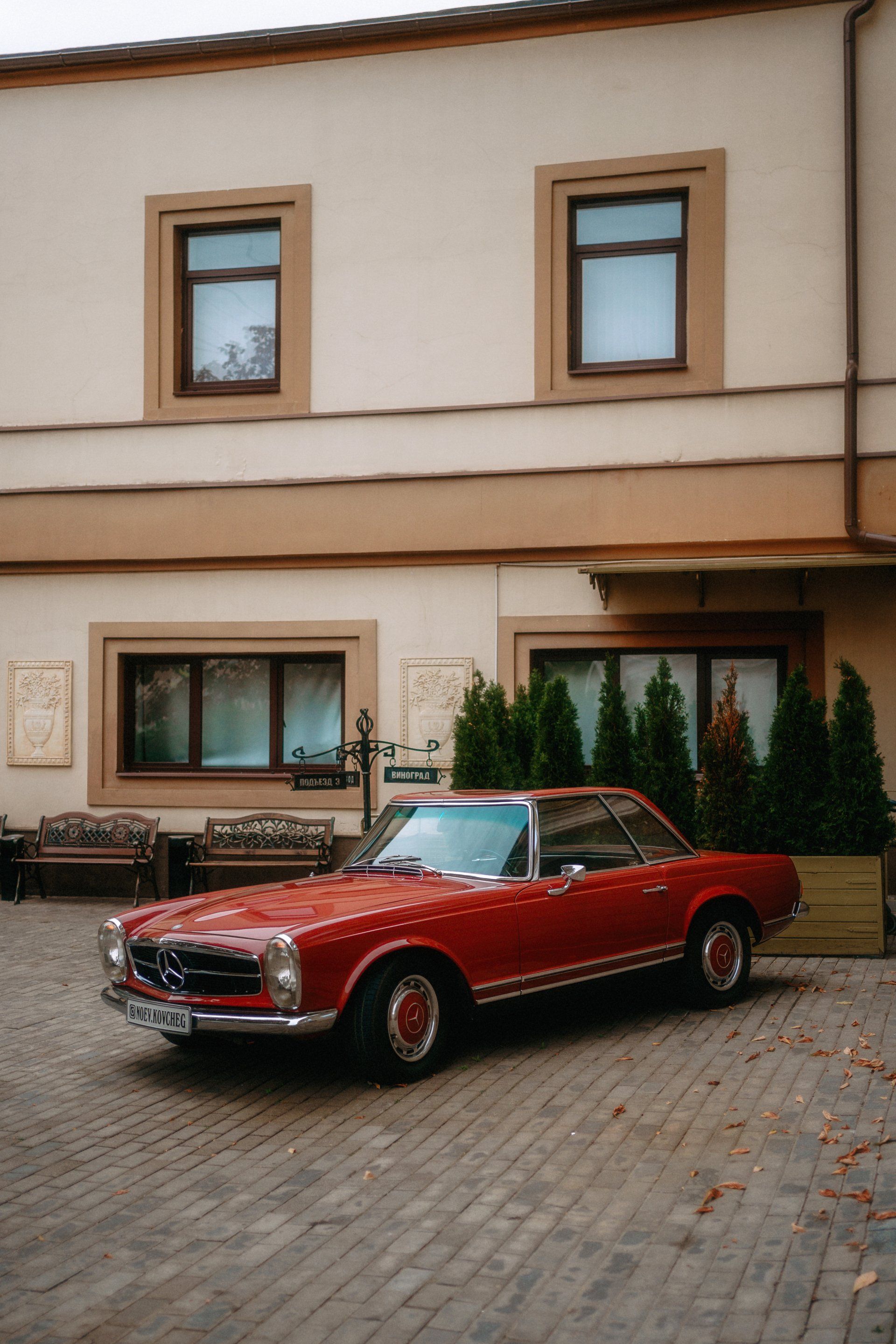 Red classic Mercedez car parked in front of building