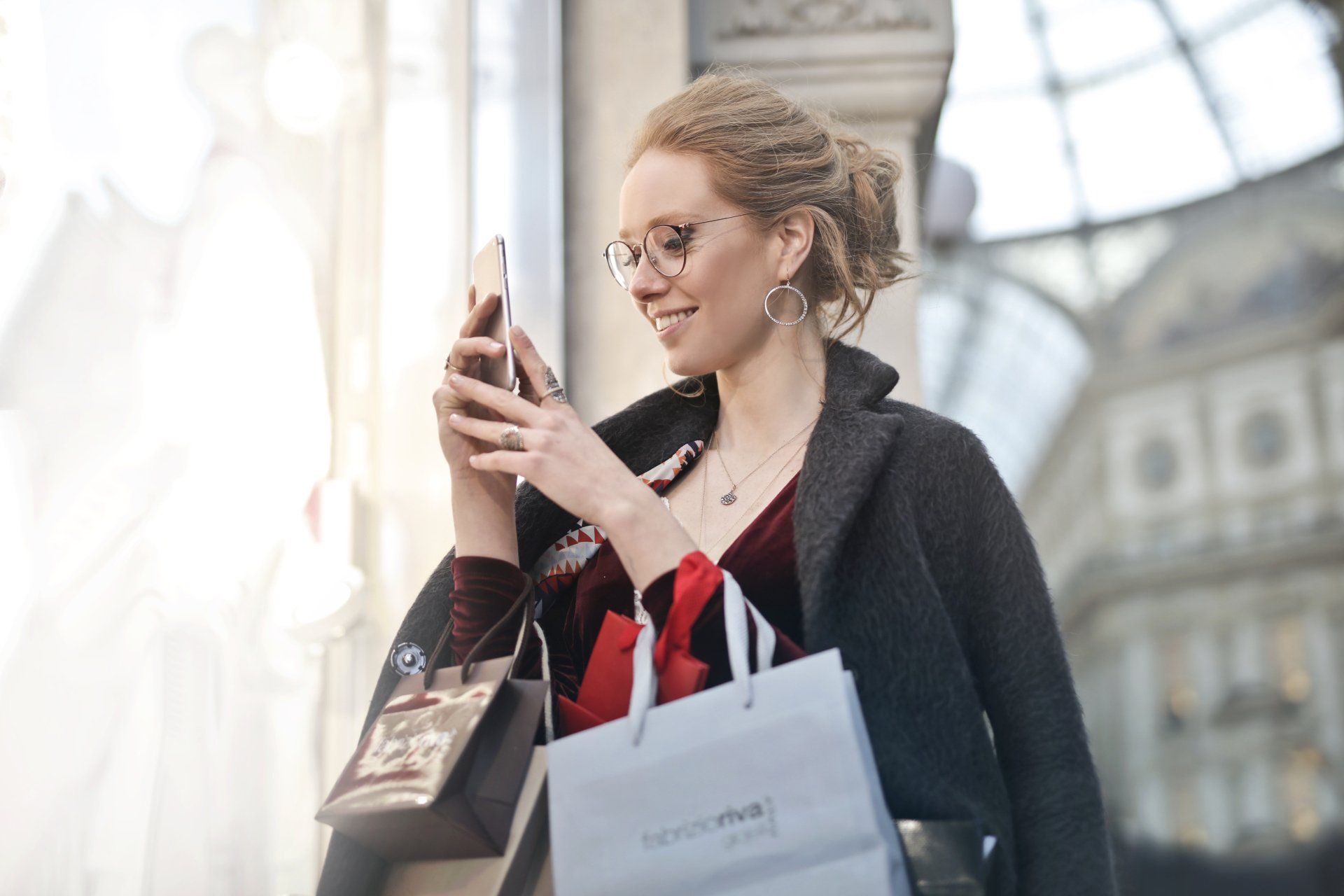 a woman is holding shopping bags and looking at her phone