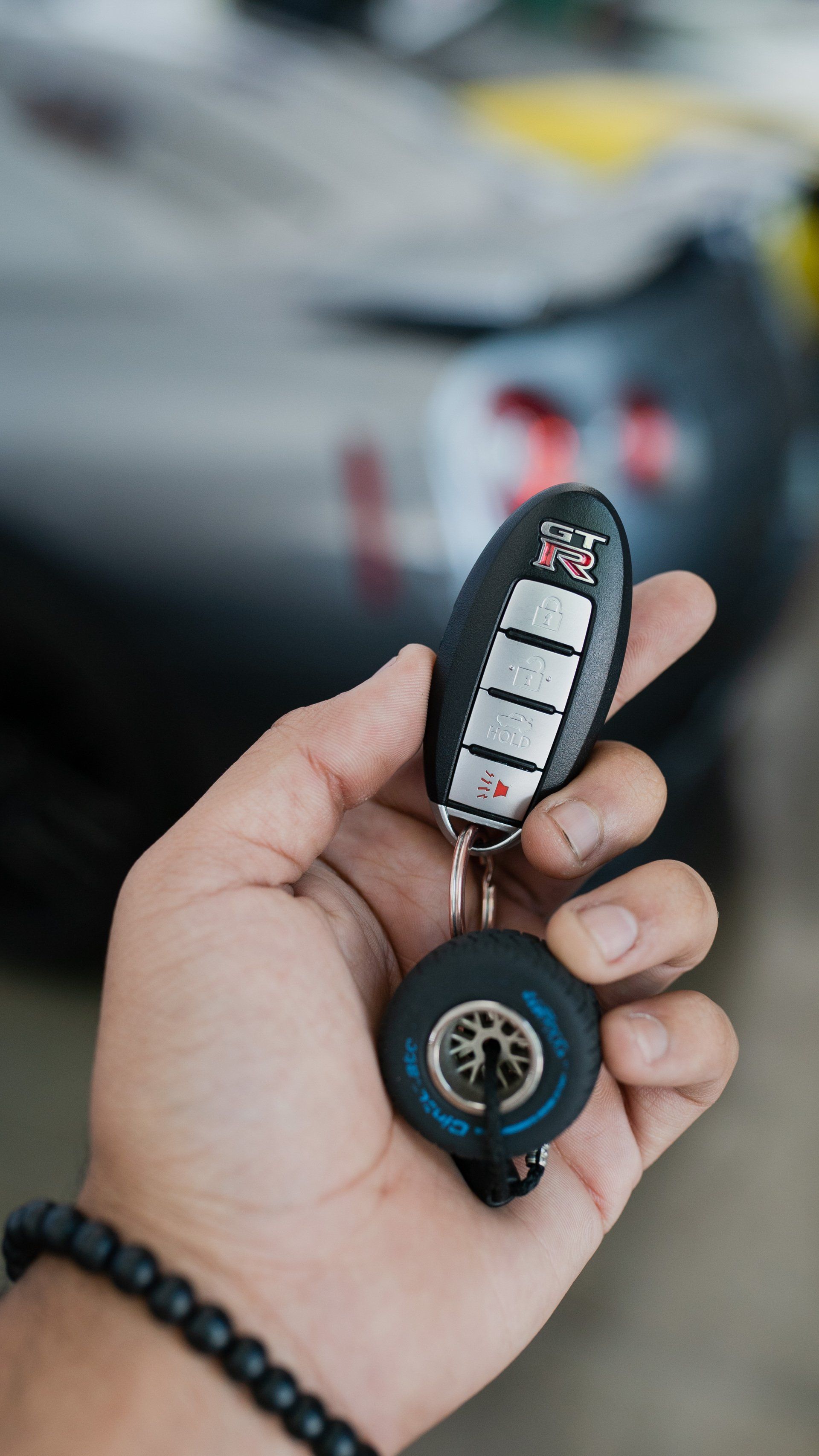 a person is holding a car key in their hand in front of a car .