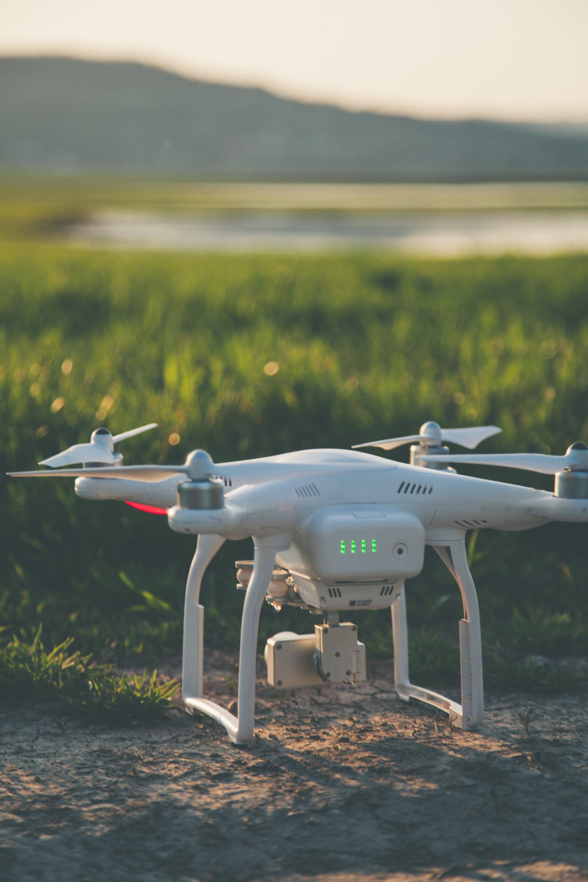 Un drone blanc est assis au sommet d'un champ de terre.