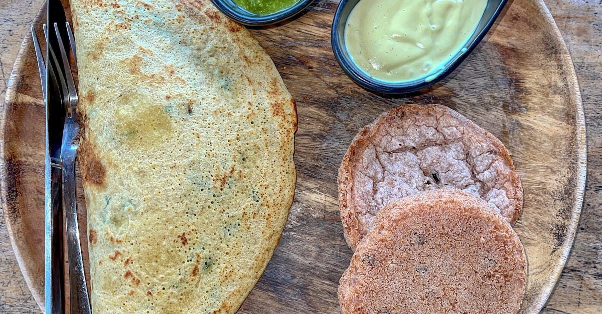 A wooden plate topped with a tortilla , a sandwich , and sauces.