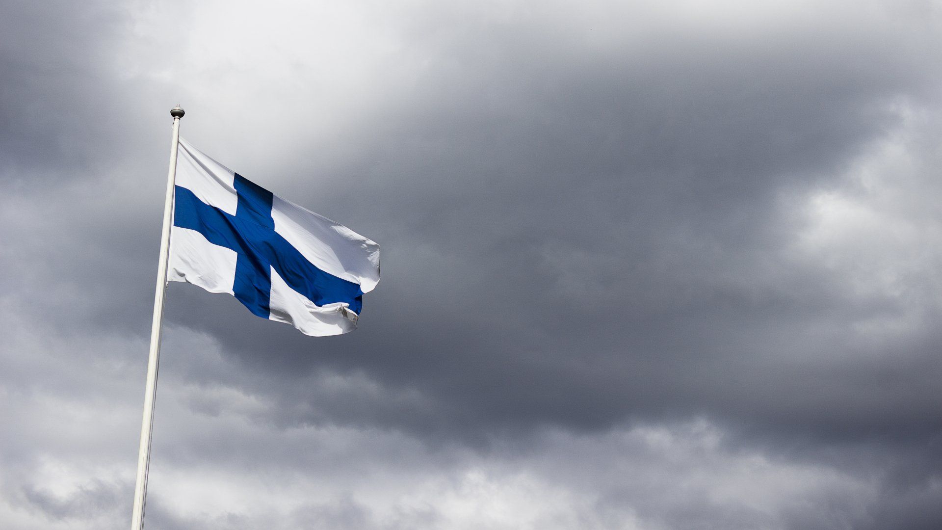 The Finnish flag waving proudly against a dramatic backdrop of storm clouds, symbolizing the resilience and strength of Finland. 