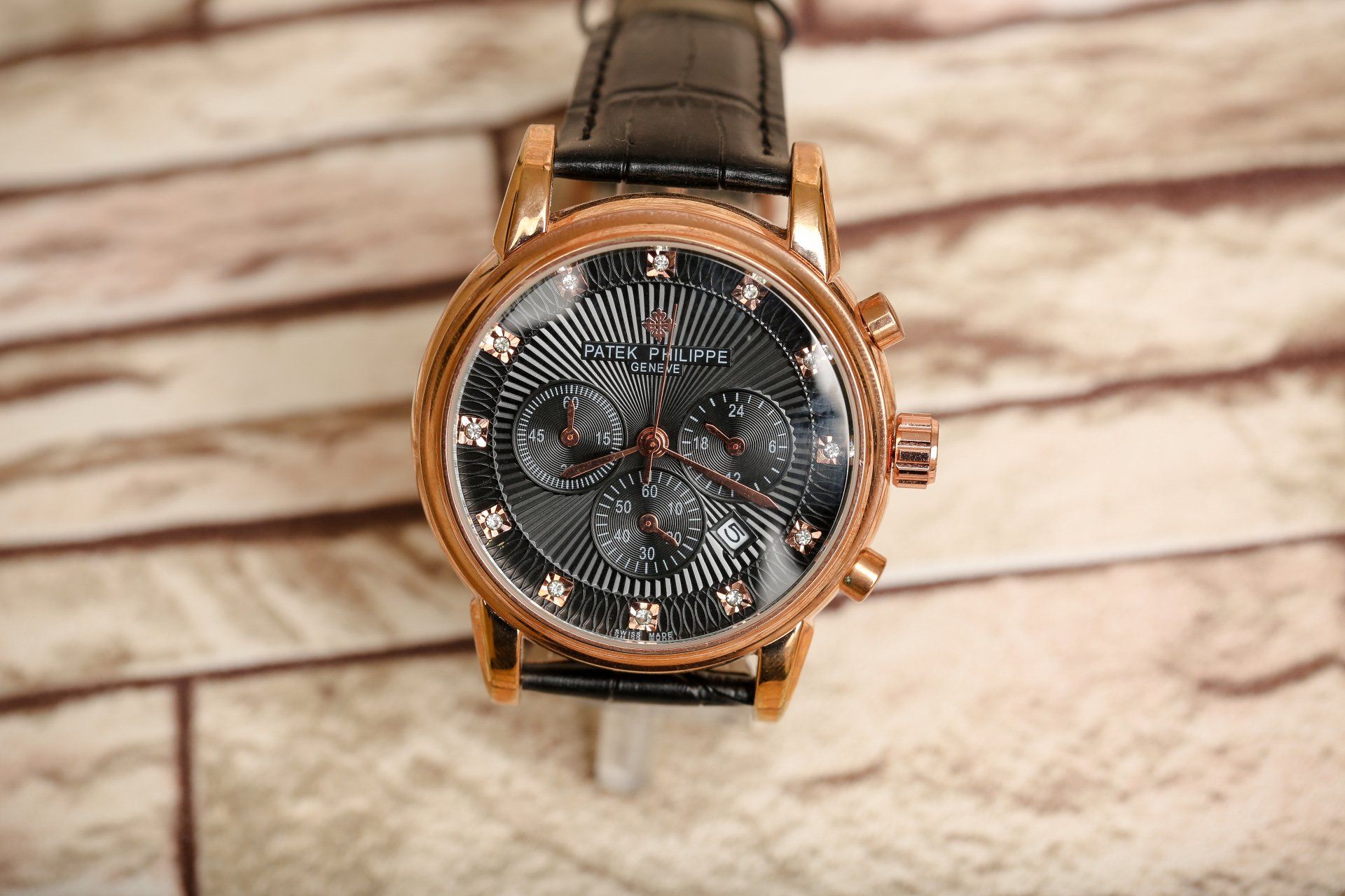 watch with brown leather strap, bronze case, and black dial
