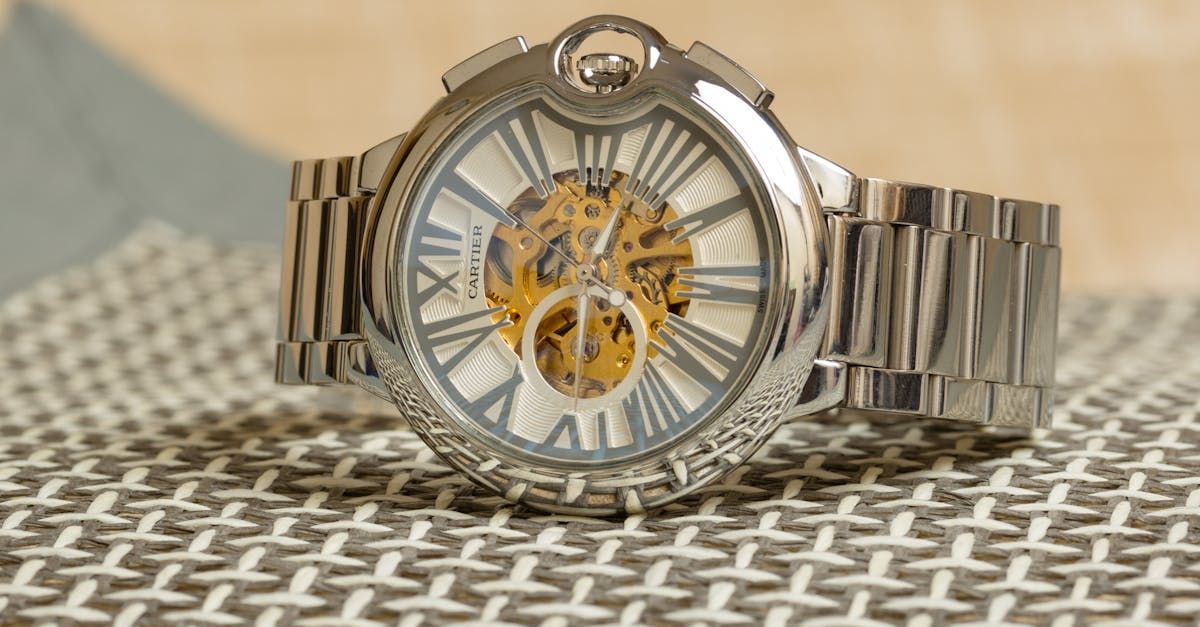 A silver watch with roman numerals is sitting on a table
