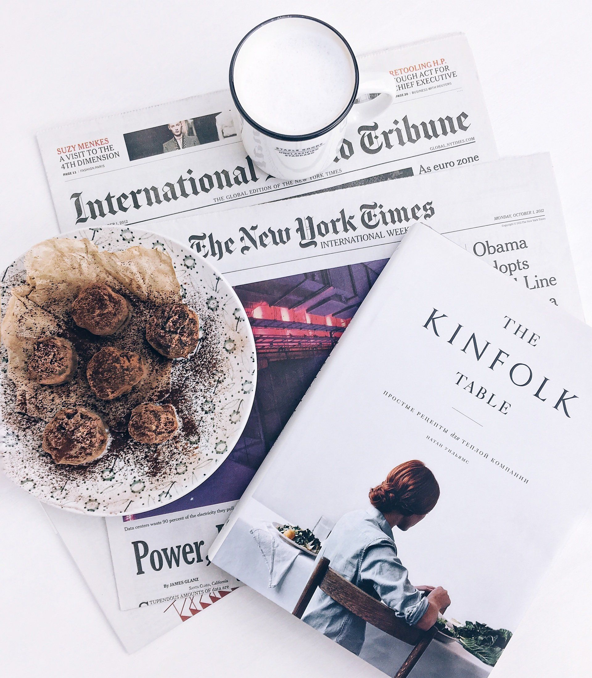 A plate of food is sitting on top of a newspaper and a book titled the kinfolk table