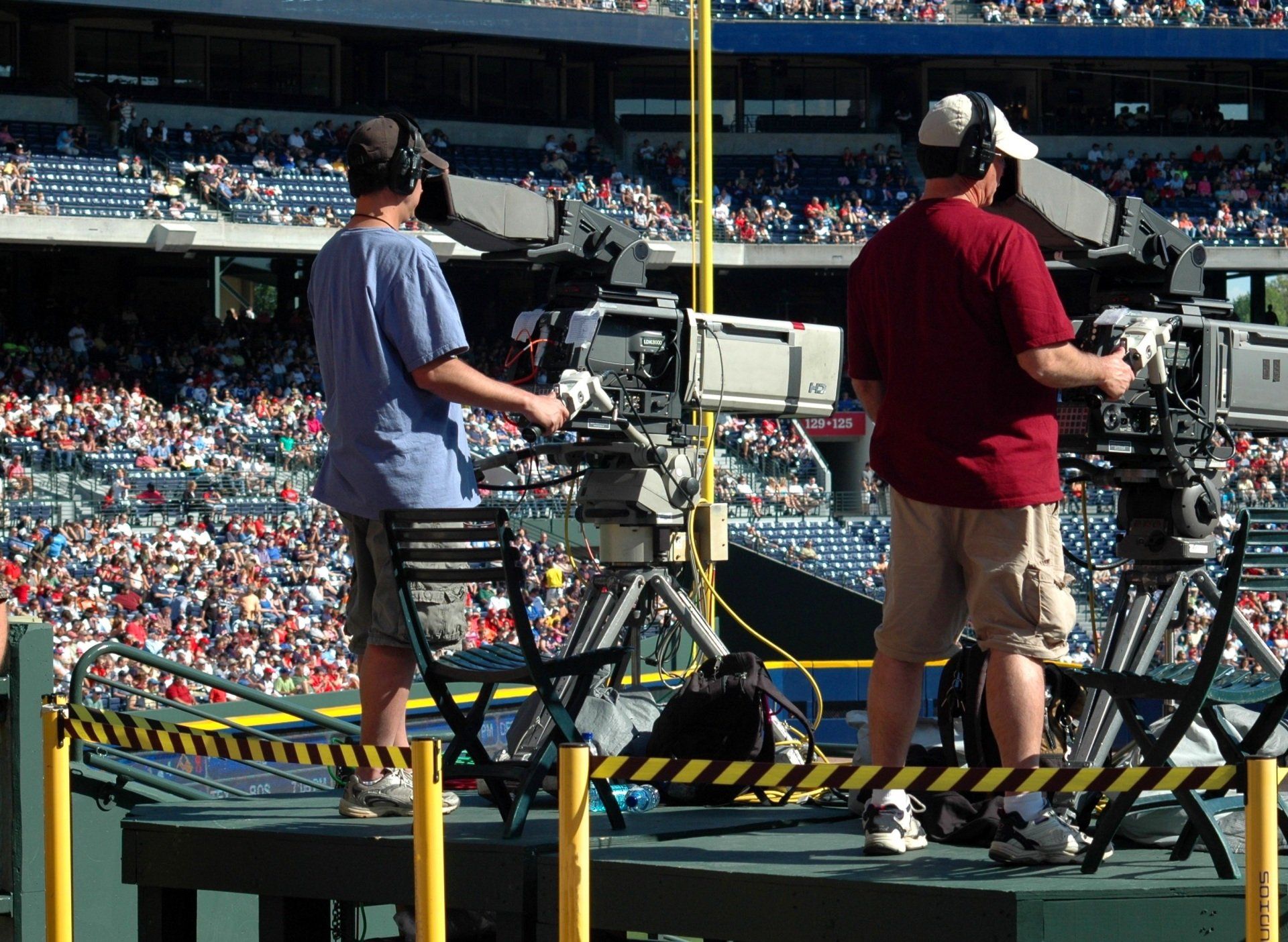 Two men are standing in front of cameras in a stadium