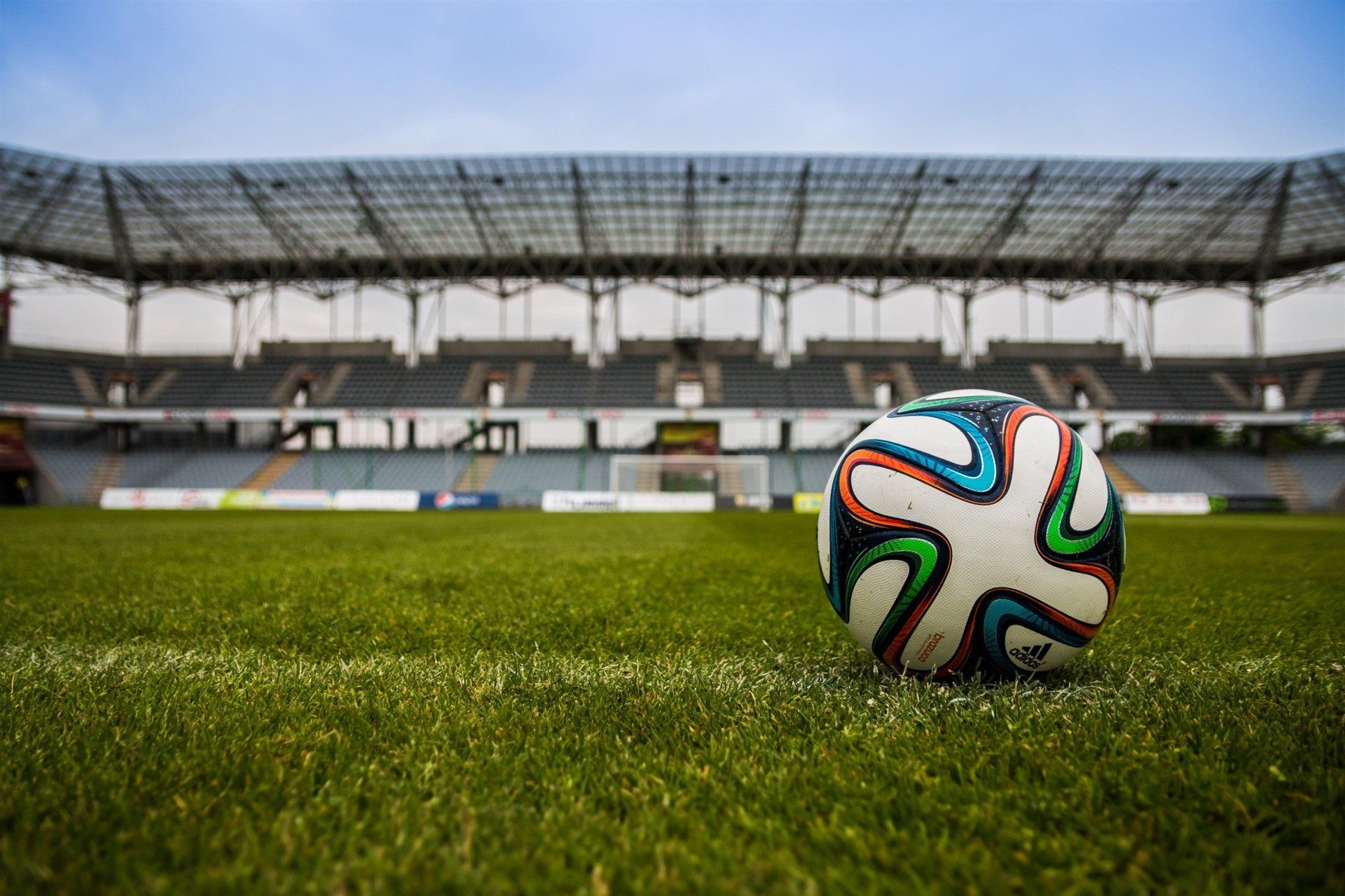 A soccer ball is sitting on the grass in front of a stadium.
