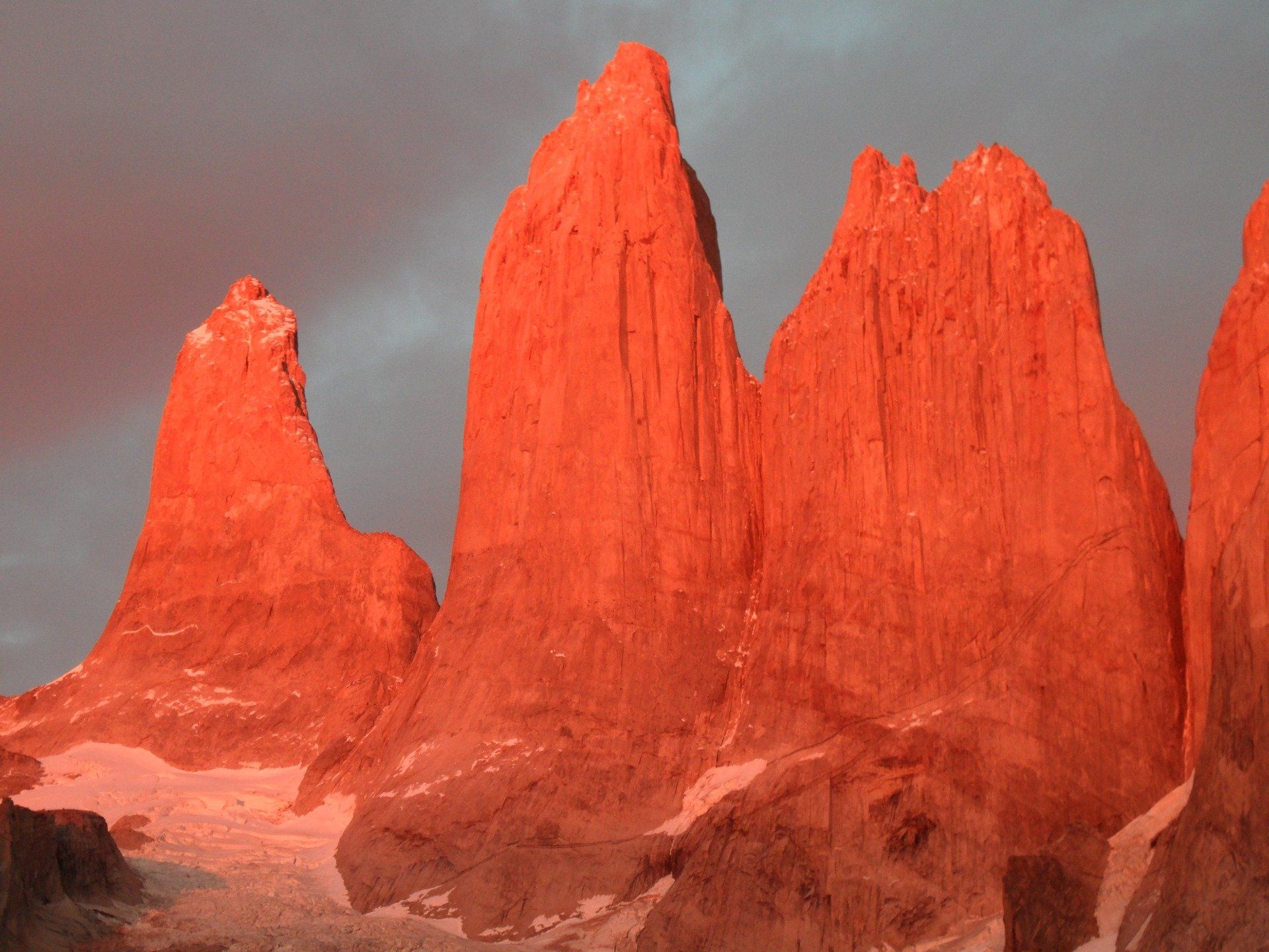 A group of red mountains with a cloudy sky in the background