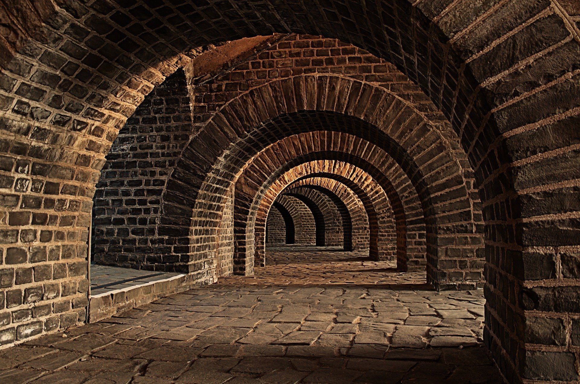 A brick tunnel with arches and a brick floor