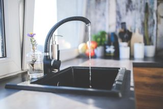 A kitchen sink with water running from the faucet.