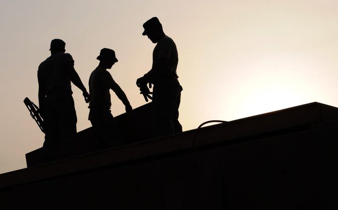 three men are standing on top of a building at sunset