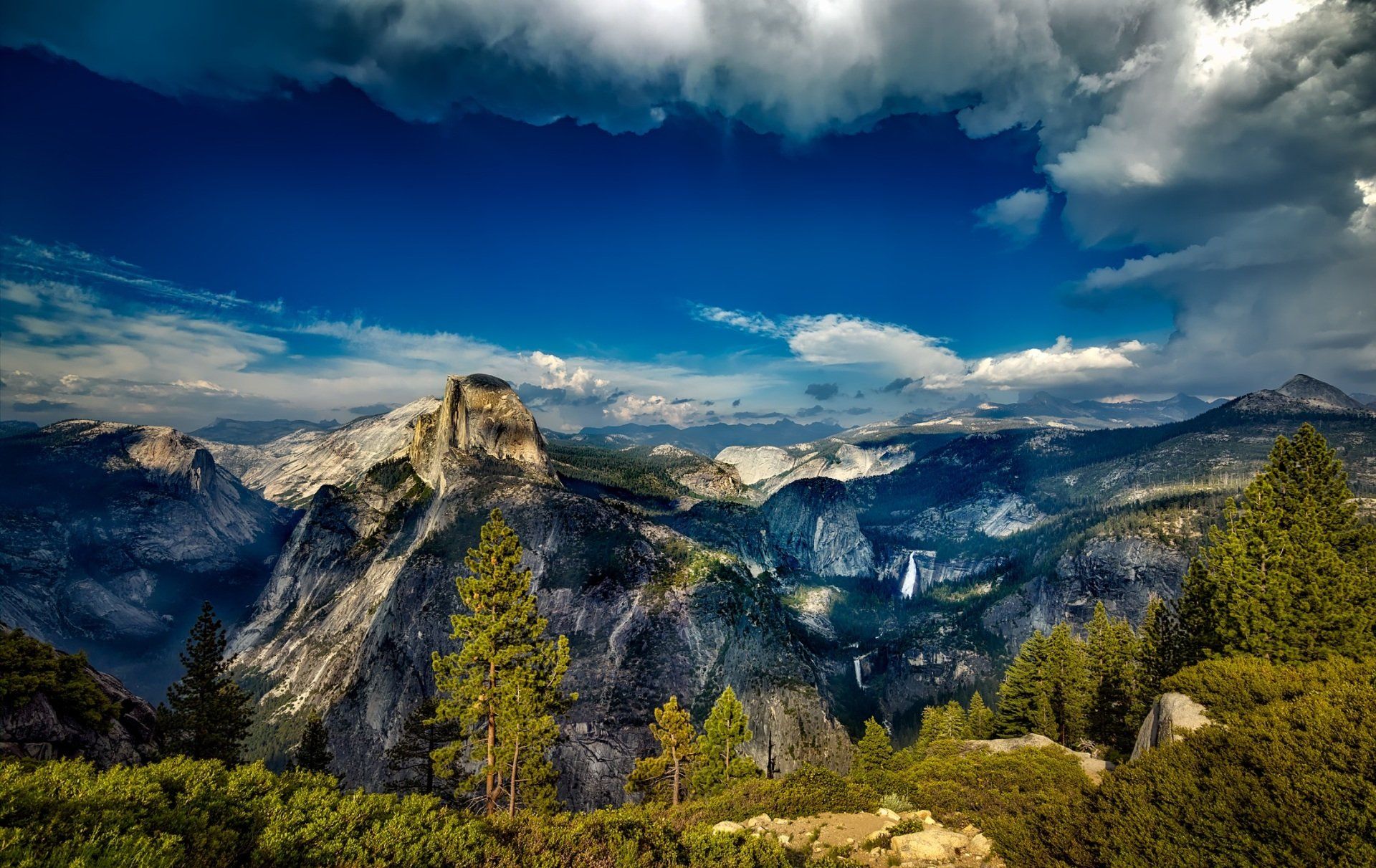 A view of a mountain range with trees and clouds in the sky.