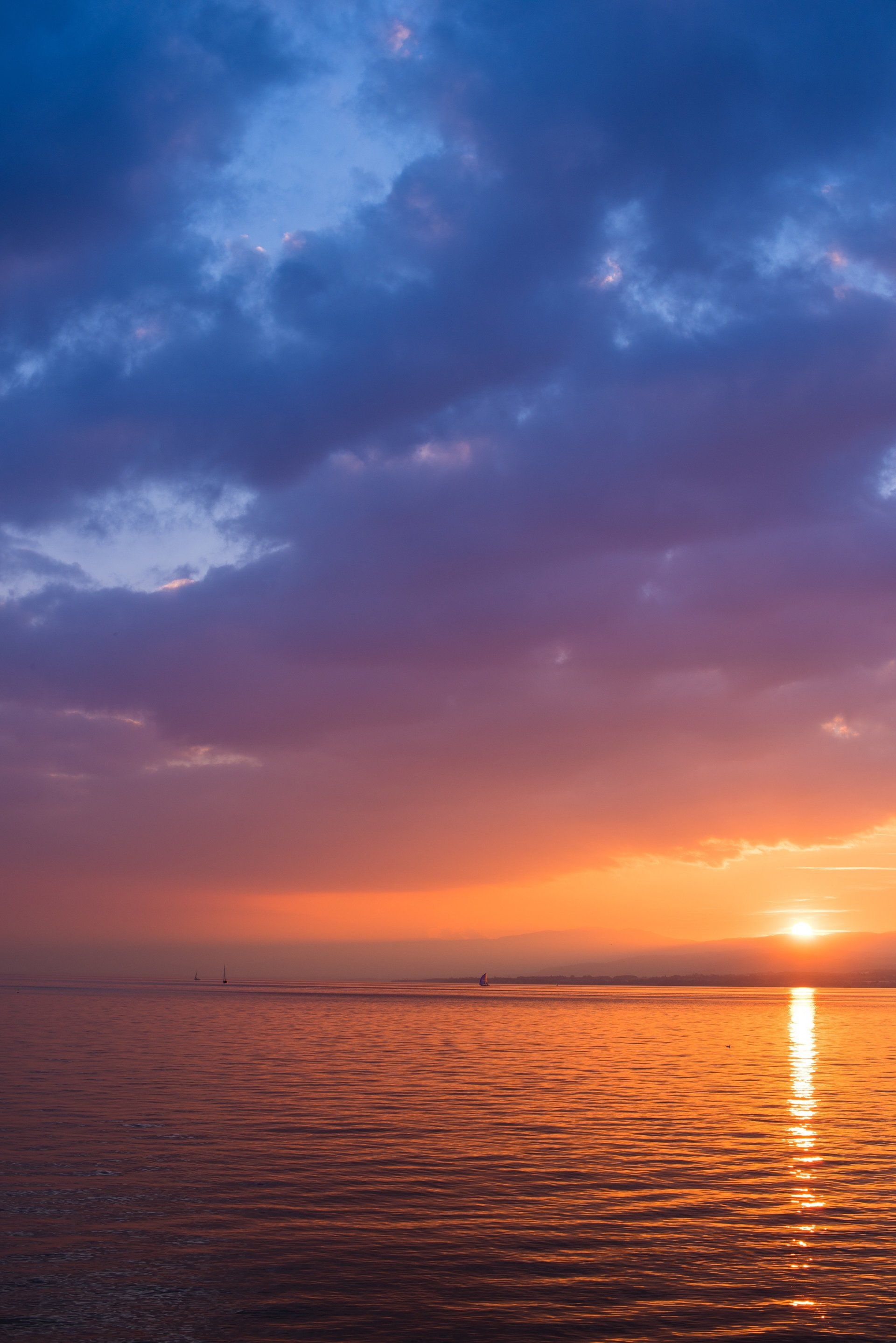 The sun is setting over the ocean with a purple and orange sky.