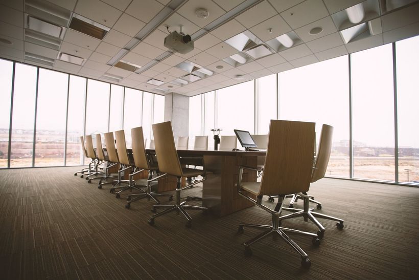 A conference room with a long table and chairs and a lot of windows.