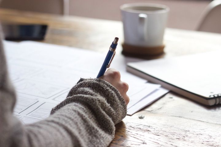 A person is writing on a piece of paper with a pen