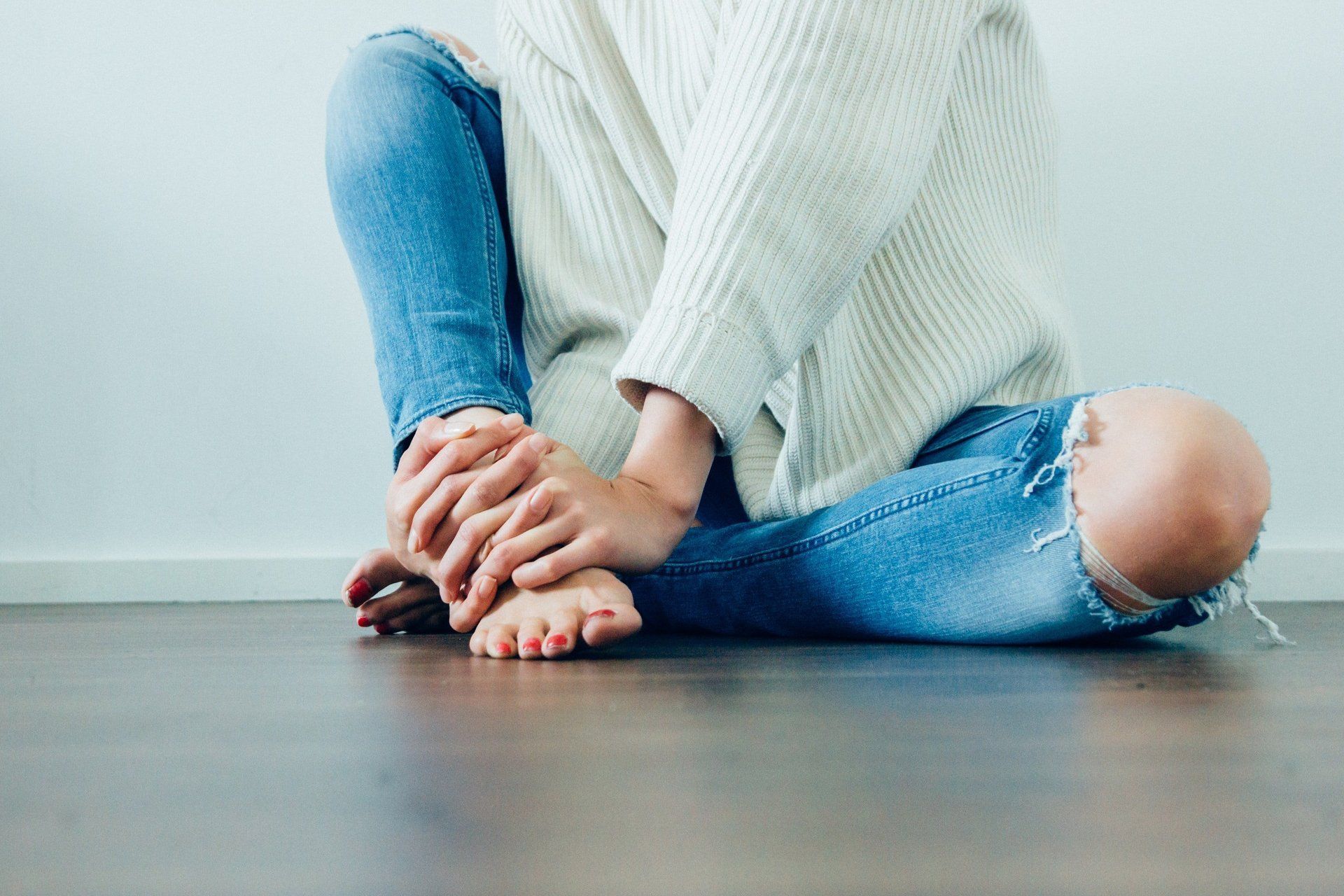 bilde som viser en person som sitter på gulvet, med smerter i foten