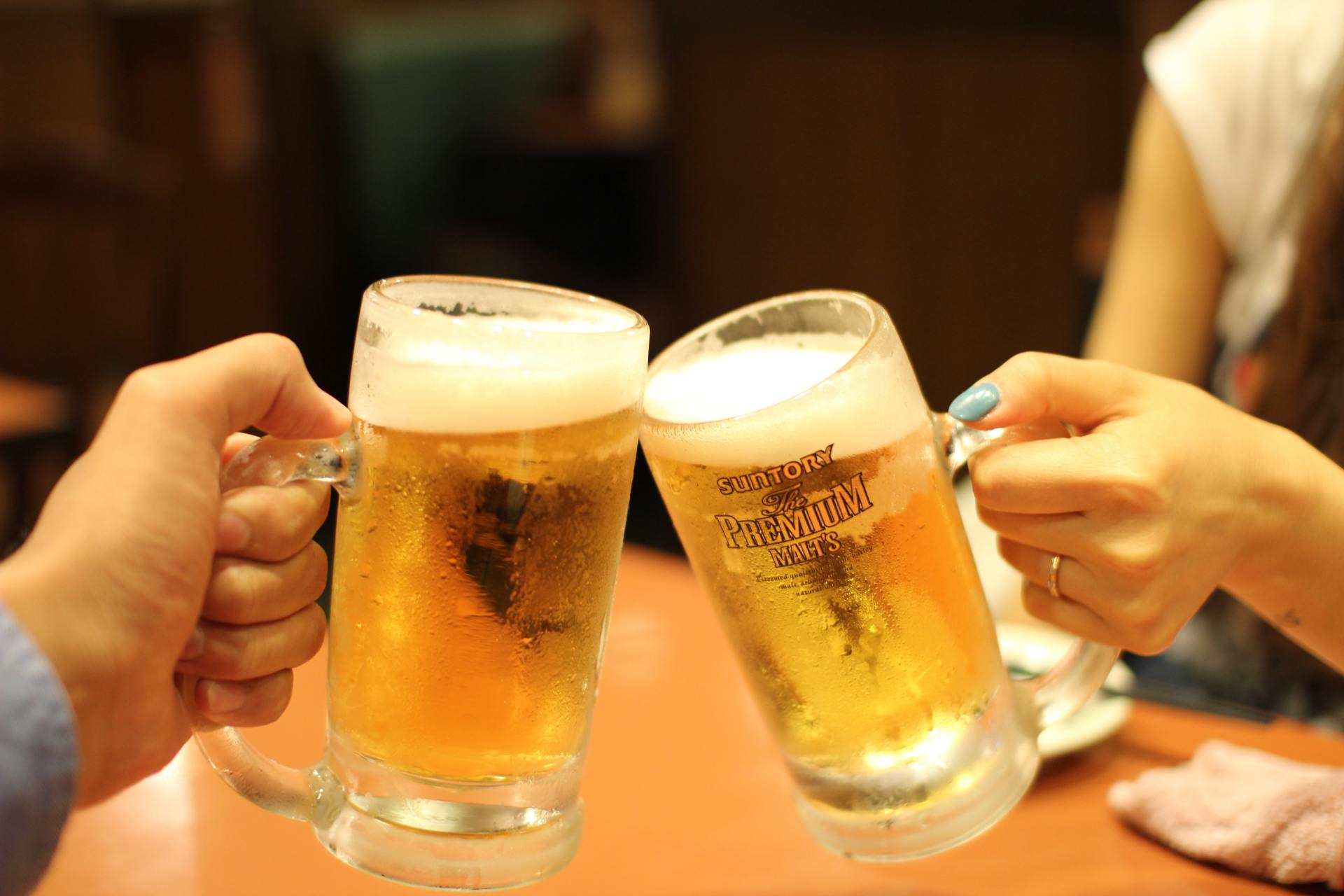 A man and a woman are toasting with two mugs of beer.