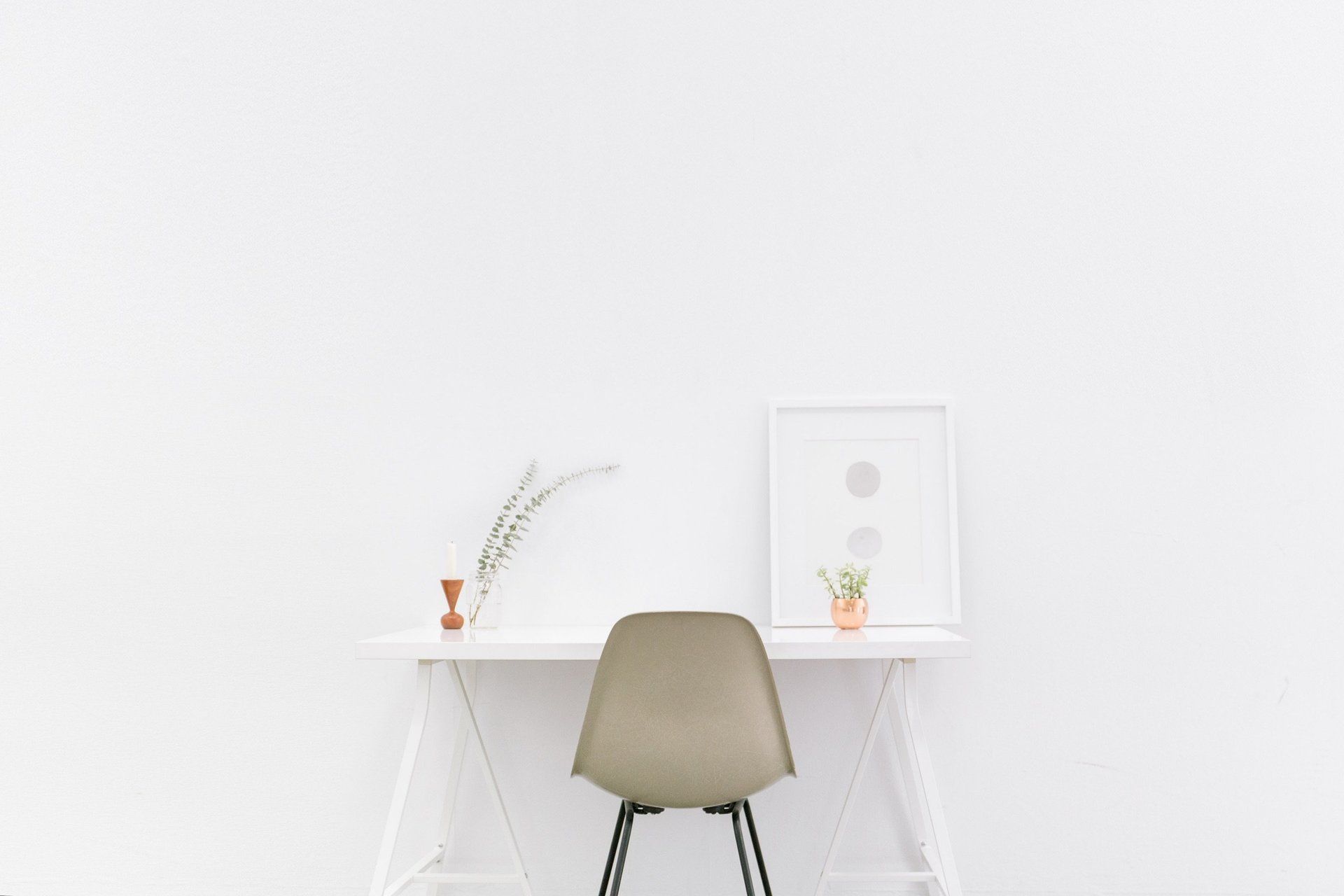 A chair at a desk in front of a white wall.