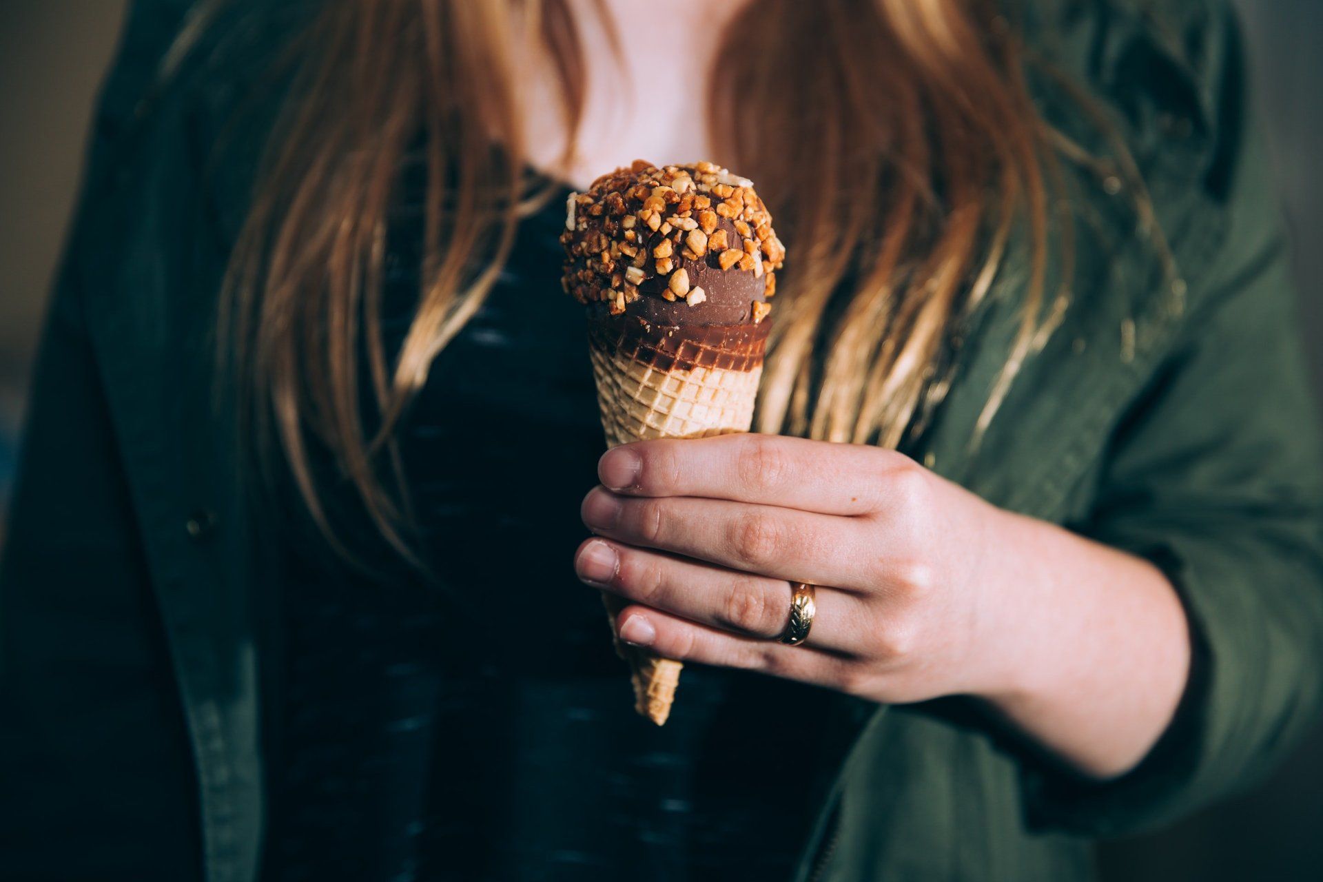 A woman is holding an ice cream cone in her hand.