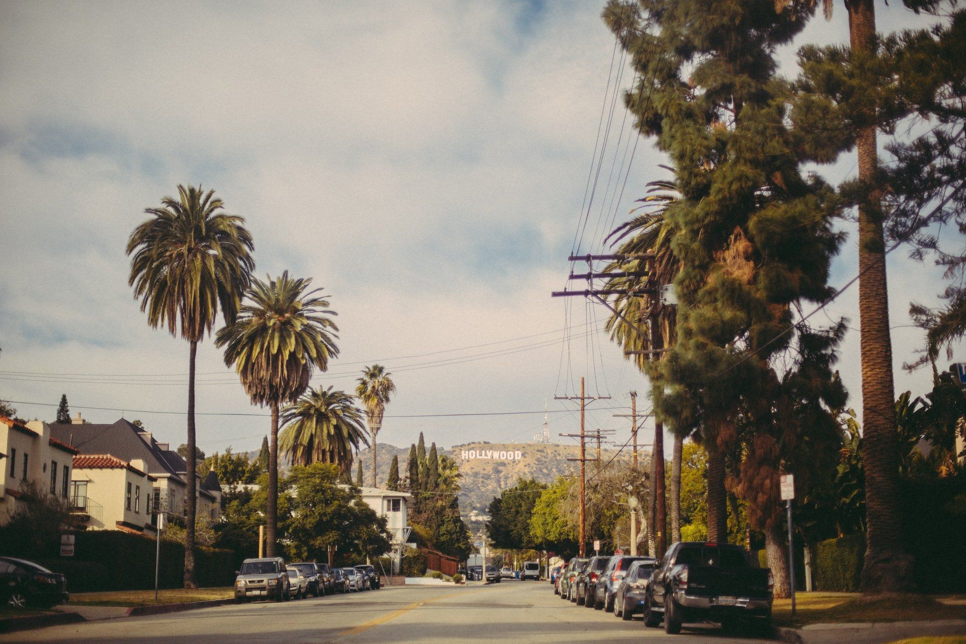 A row of cars are parked on the side of a street.