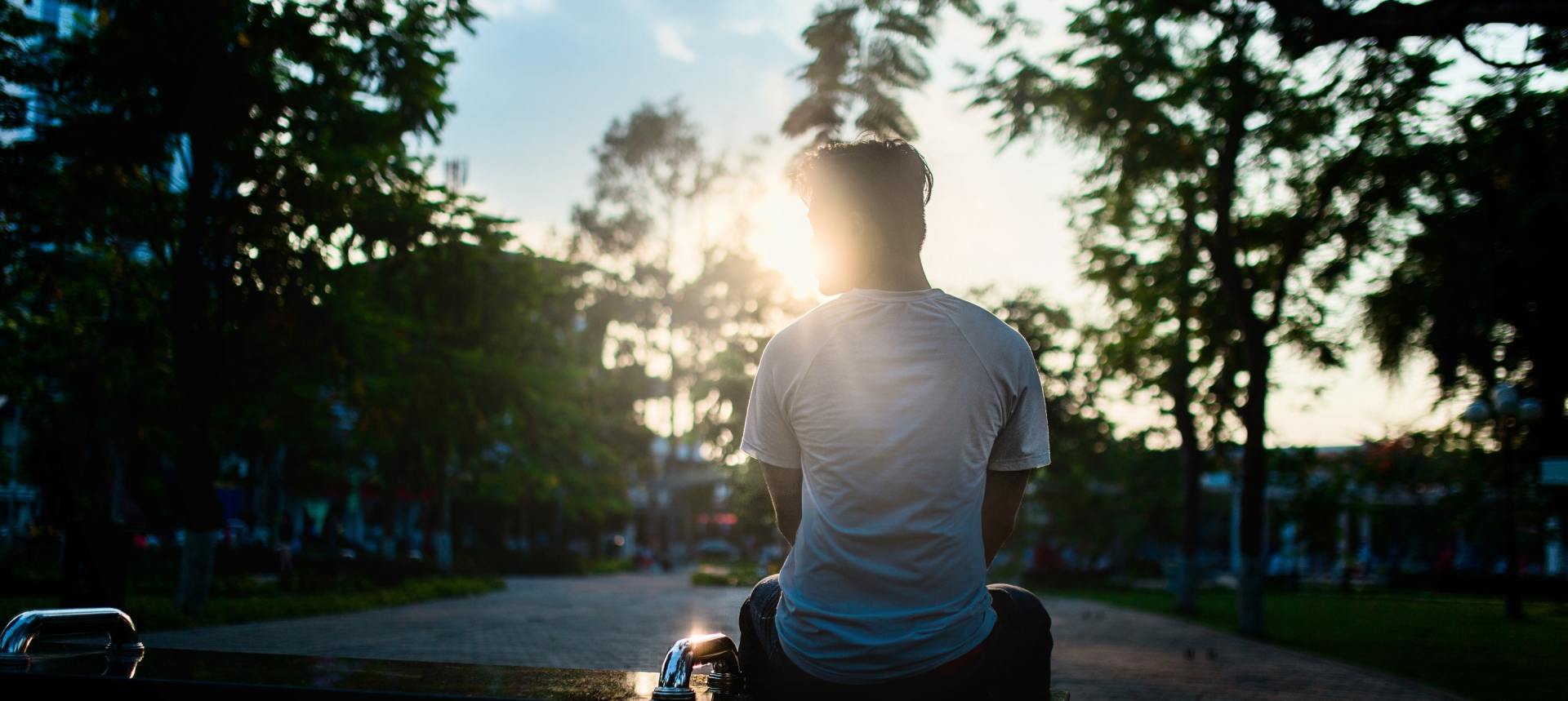 A man is sitting on a motorcycle looking at the sun.