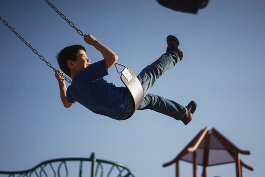young boy on swing up in air with smile